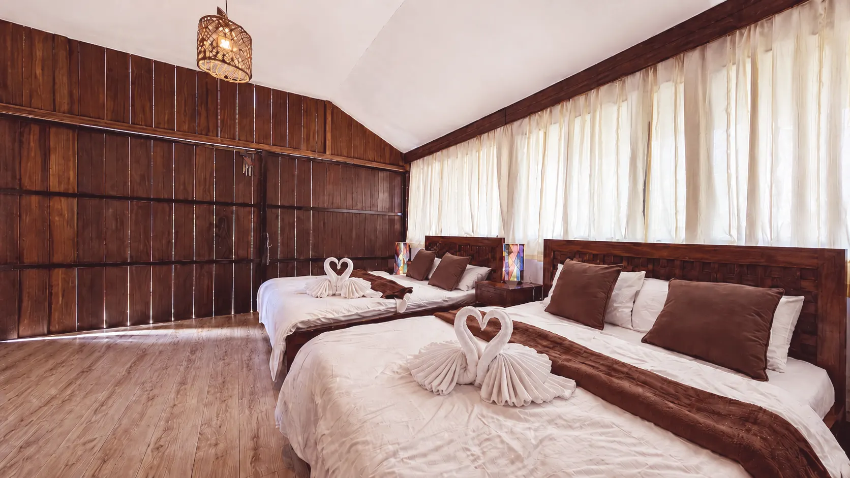 Two queen-size beds with white linens inside San Jose Cabins